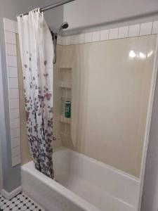 El baño incluye bañera blanca con cortina de ducha. en The Lodge@ Kendon, en Lansing