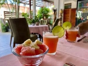 a table with a bowl of fruit and two drinks at Villa Famiri Boutique hotel in Paramaribo