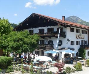 ein Gebäude mit Tischen und Sonnenschirmen davor in der Unterkunft Gasthof Ochsenwirt in Oberaudorf