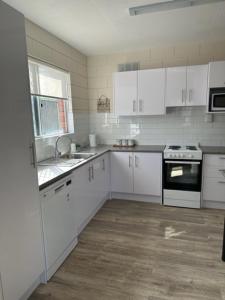 una cucina con armadi bianchi, lavandino e piano cottura di Harbour View 49 Urch Street Unit 8 a Geraldton