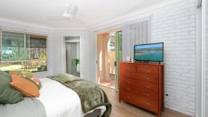 a bedroom with a bed and a television on a dresser at The Point in Iluka