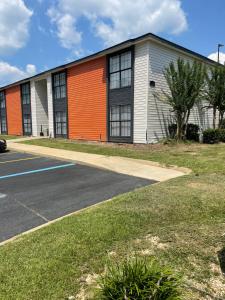 an orange and white building with a parking lot at Ramada by Wyndham Studio Suites Dothan in Dothan