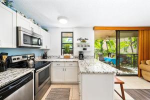 une cuisine avec des placards blancs et un comptoir dans l'établissement Big Island Kona Makai 4205 condo, à Kailua-Kona