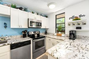- une cuisine avec des placards blancs et des comptoirs en granit dans l'établissement Big Island Kona Makai 4205 condo, à Kailua-Kona