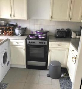 a kitchen with white cabinets and a stove top oven at The Right Place. A Fabulous/Cozy Double Room in London