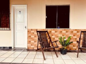 two chairs sitting outside of a house with a window at Hospedagem Serra da Lua in Alter do Chao