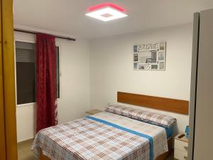 a bedroom with a bed and a red curtain at Piso cerca de la playa. in Melilla