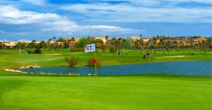 a green golf course with a sign in front of a pond at Herdade dos Salgados Harmonia in Guia