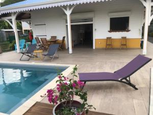 a purple lounge chair next to a swimming pool at Bungalow Candy avec piscine in Rivière-Salée