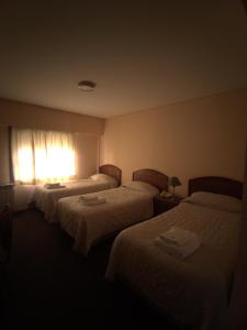 コモドーロ・リバダビアにあるHotel Victoriaのベッド3台と窓が備わるホテルルームです。