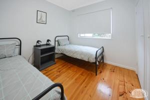 a bedroom with two beds and a wooden floor at Hook, Wine & Linger on Learmonth in Portland