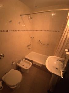 a bathroom with a toilet and a sink and a tub at Hotel Victoria in Comodoro Rivadavia