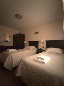 Habitación de hotel con 2 camas con sábanas blancas en Hotel Victoria en Comodoro Rivadavia
