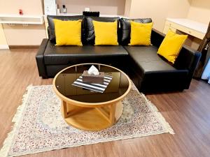 - un canapé noir avec des oreillers jaunes et une table basse dans l'établissement Bangkok Downtown 2bedrooms3bth Near Asoke Btsmrt No1, à Bang Kapi