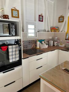a kitchen with white cabinets and a stove top oven at Bungalow Candy avec piscine in Rivière-Salée