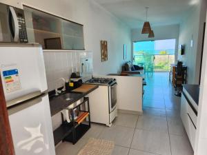 uma cozinha com electrodomésticos brancos e uma sala de estar em Mahalo residence vista mar em Porto de Galinhas
