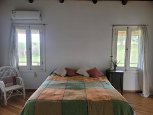 a bedroom with a large bed and two windows at Casa en barrio de Chacras Las Perdices in Carmelo