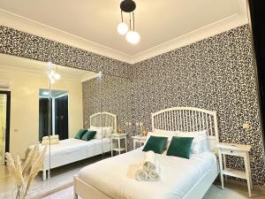 - une chambre avec 2 lits et un mur recouvert de papier peint dans l'établissement Greeny view in cosy 3BDR - downtown near train / tram, à Casablanca