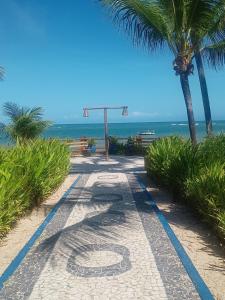 een loopbrug op een strand met palmbomen en de oceaan bij Bella casa 10 em Guarajuba, apartamento equipado para você e sua família, tudo que você precisa pra se sentir em casa! in Guarajuba