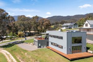 a house on a hill with mountains in the background at Black Diamond - Luxury Alpine Home in Merrijig - Sleeps 14 in Merrijig