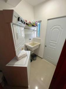 a small white bathroom with a sink and a refrigerator at Lovely 3-Bedroom Condo with FREE Parking/Laundry in Santiago de los Caballeros