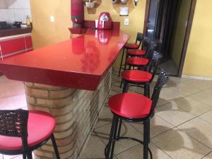 uma fila de bancos vermelhos num bar num restaurante em Sítio Santa Terezinha em Divinópolis
