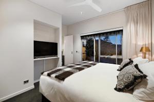 a white bedroom with a large bed and a large window at Queenstown Hot Tub Apartment in Frankton Wharf