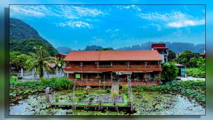 a wooden house with a red roof in a field at Trang An Homestay in Ninh Binh