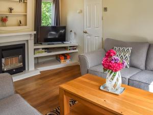 a living room with a vase of flowers on a coffee table at Meadow View Van - Uk44667 in Neatishead