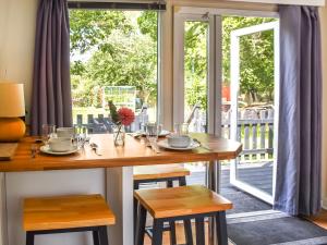a wooden table with two chairs and a porch with a door at Meadow View Van - Uk44667 in Neatishead