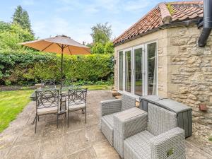 a patio with a table and chairs and an umbrella at Forge Gardens in Thornton Dale