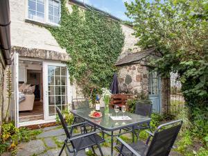 a patio with a table and chairs in front of a building at Mayrose Cottage in Lanteglos