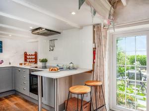 a kitchen with a counter and two stools in front of a window at Mayrose Cottage in Lanteglos