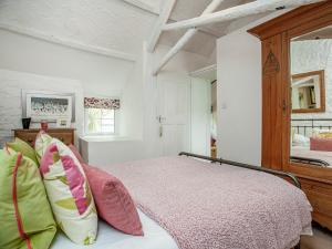 a bedroom with a bed with colorful pillows at Mayrose Cottage in Lanteglos