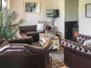 a living room with leather couches and a fireplace at Harperfield Chalet in Lanark