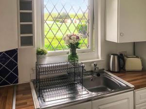 a kitchen sink with a vase of flowers on the window at Harperfield Chalet in Lanark
