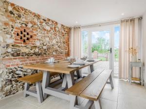 a dining room with a table and a brick wall at The Granary in Great Fransham