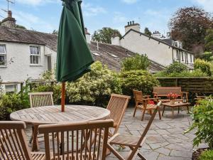 un patio con mesa, sillas y sombrilla en Corner Cottage, en Bowness-on-Windermere