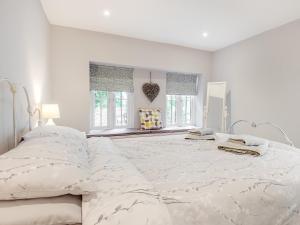 a white bedroom with a large bed with white sheets at The Granary in Great Fransham