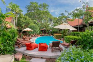 einen Pool mit Stühlen und Sonnenschirmen vor einem Haus in der Unterkunft Baan Duangkaew Resort in Hua Hin