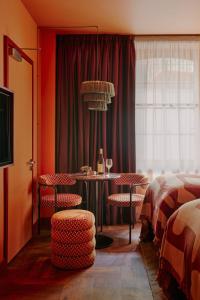 ロンドンにあるEmber Locke Kensingtonのテーブル、椅子、ベッドが備わる客室です。