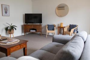 a living room with a couch and a tv at Basedow Units Tanunda in Tanunda