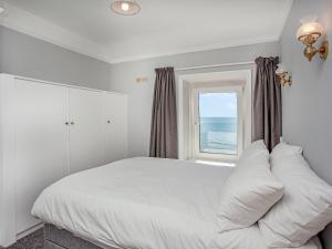 a bedroom with a large white bed with a window at Ocean View, Coastguard Cottages in Dawlish