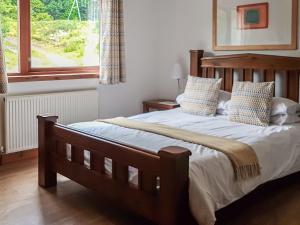 um quarto com uma cama de madeira com almofadas e uma janela em Beech House em Torcastle