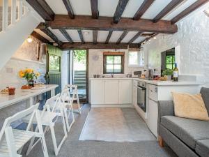 uma cozinha com armários brancos e um sofá e cadeiras em The Granary em Stokeinteignhead