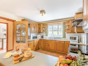 a kitchen with wooden cabinets and a table with fruits at Cysgod Y Capel in Cerrigydrudion