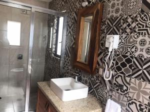 een badkamer met een wastafel, een douche en een spiegel bij Cabaña Lunamiel 3 in Mazamitla