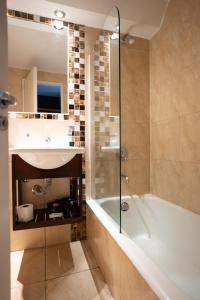 a bathroom with a tub and a sink at Hotel Sol Bariloche in San Carlos de Bariloche