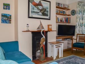 a living room with a blue couch and a fireplace at Windward House in Salcombe