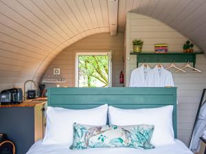 a bedroom with a bed with a blue headboard and a window at Knowstone-uk40034 in East Anstey